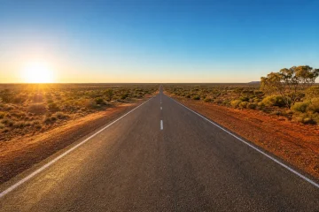 Soluppgång över en rak väg genom den australiska outbacken